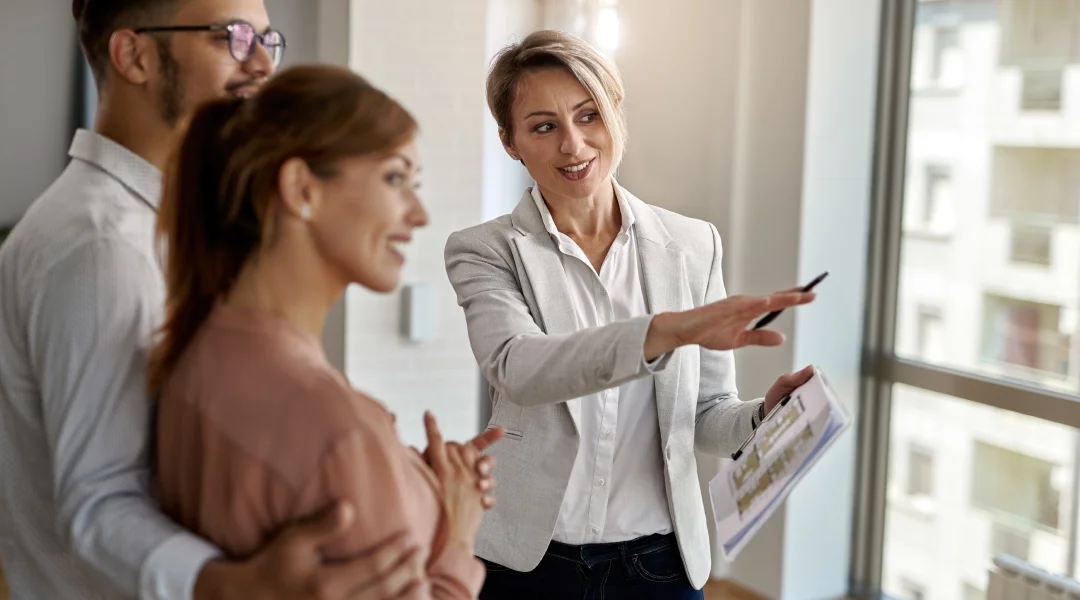 A woman points to a document while two other people observe her in a professional setting.