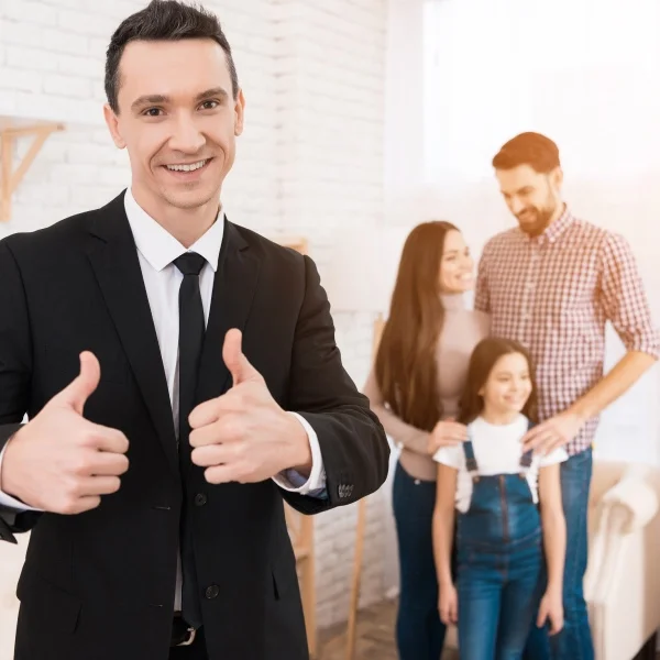 Un homme en costume et cravate se tient devant sa famille souriante.