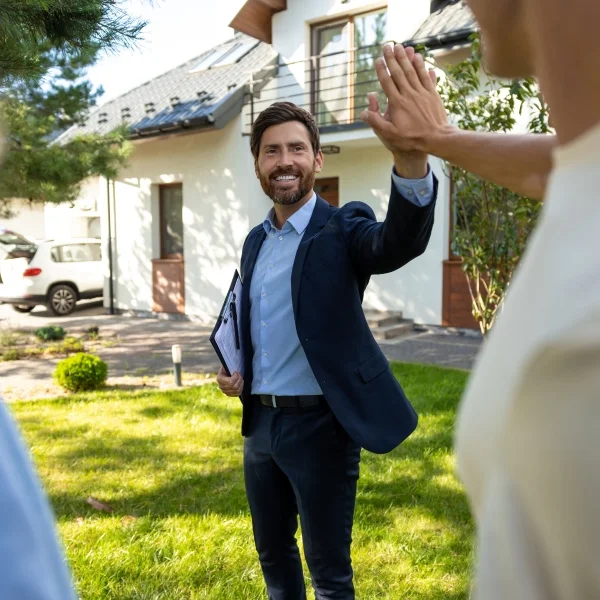 Comment préparer votre propriété pour une vente rapide 3 Un homme en costume fait un high five à un autre homme, exprimant la camaraderie et la célébration.